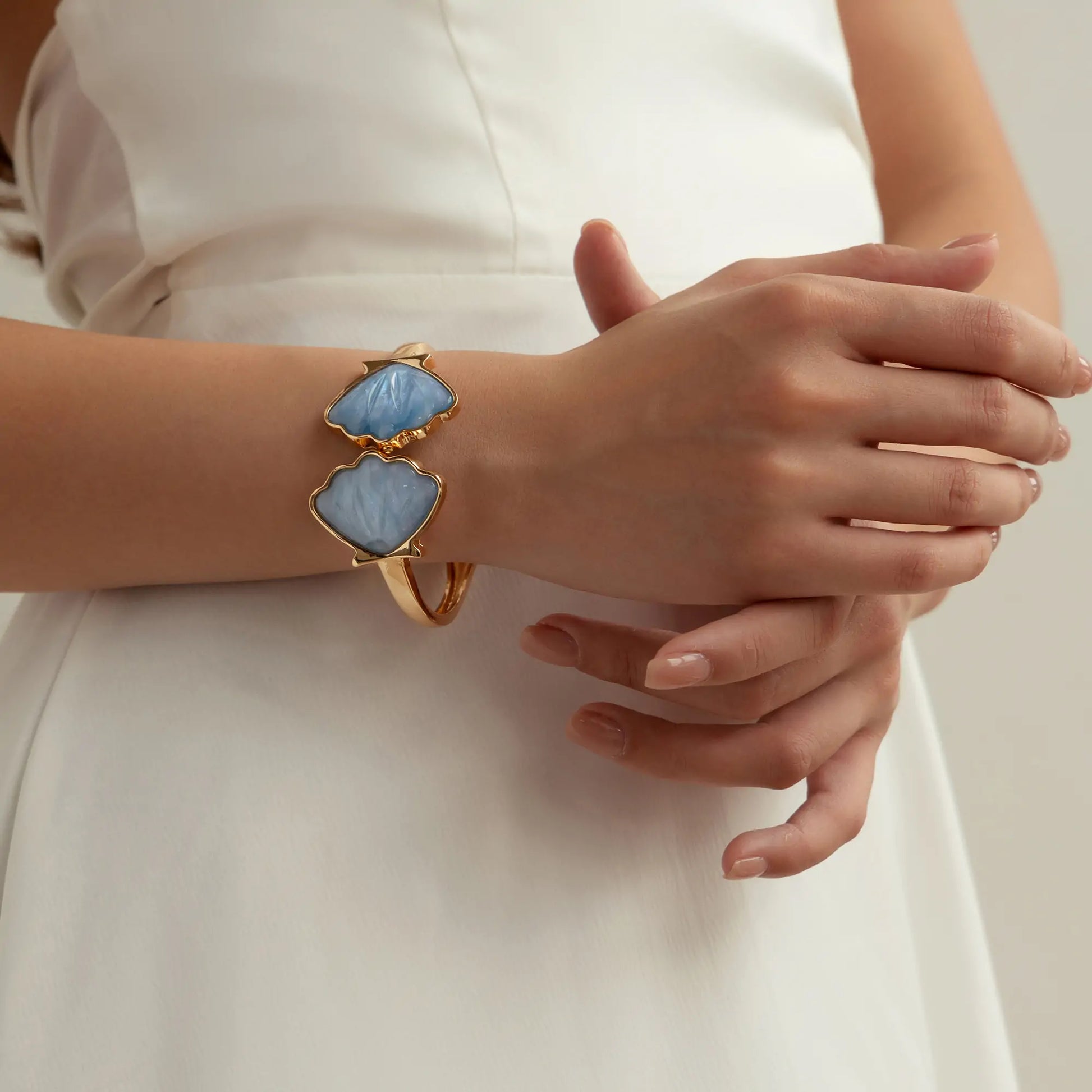An upward view of the female wrist wearing a seashell bracelet under indoor lighting