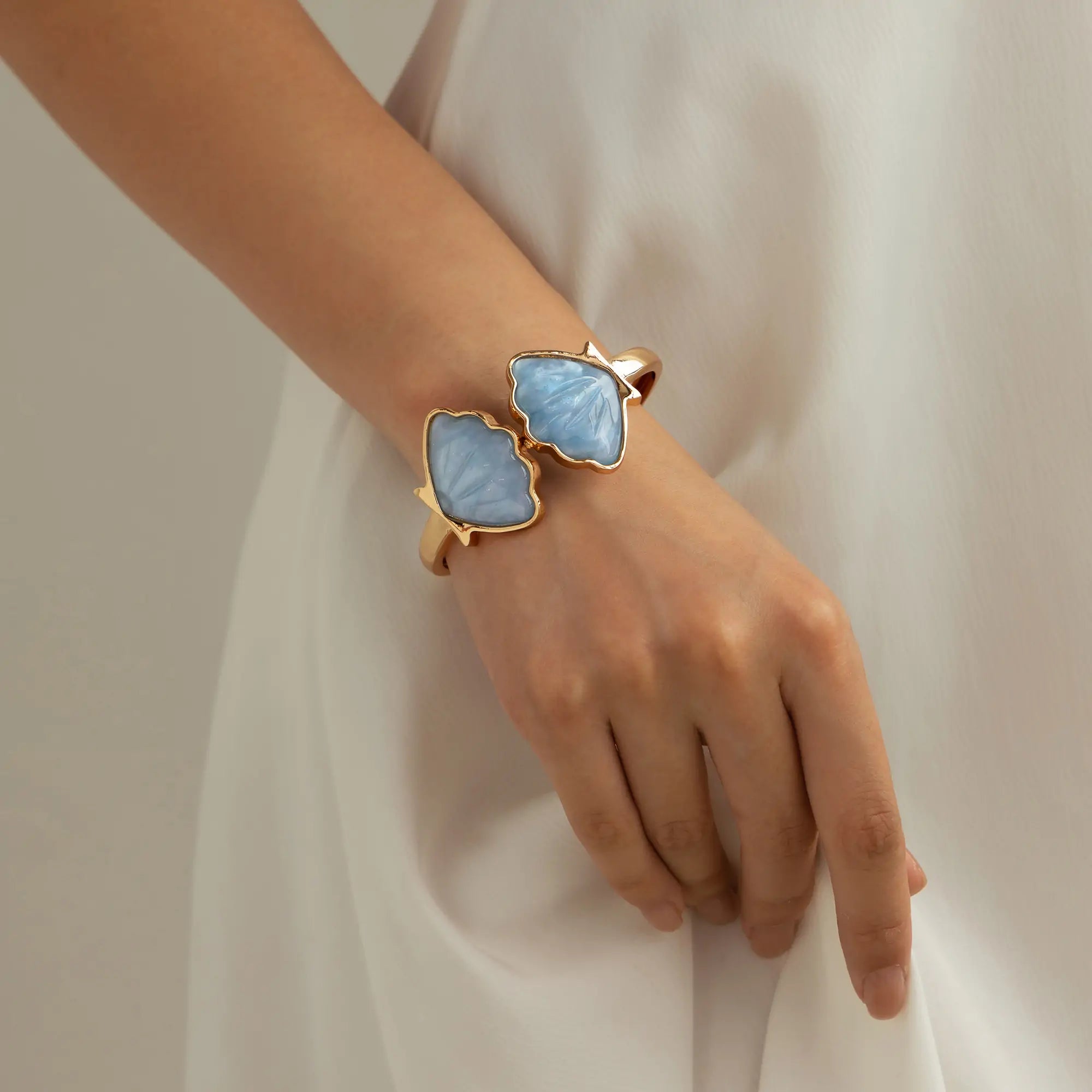 Under soft indoor lighting, a close-up of the wrist wearing a seashell bracelet